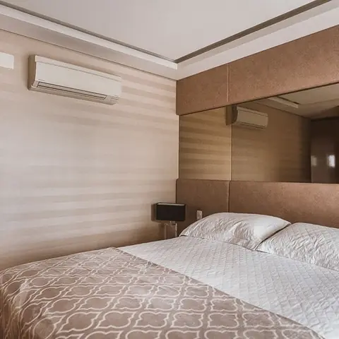 Suíte com ar-condicionado split e painel espelhado